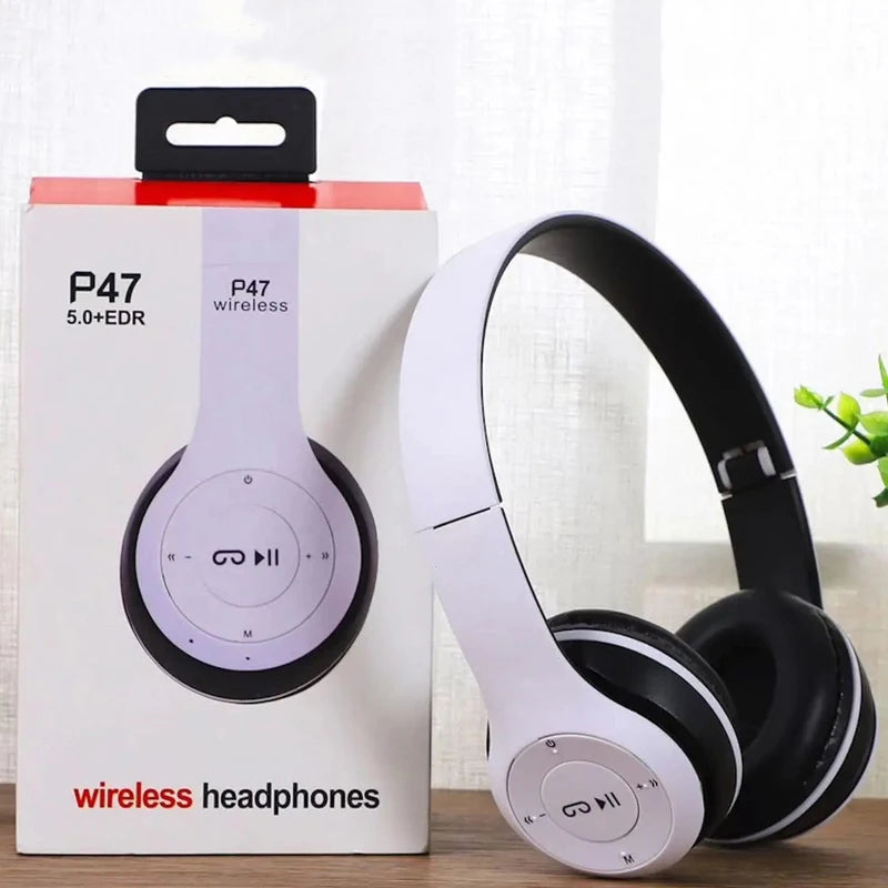 White and black wireless headphones next to their packaging on a light surface.